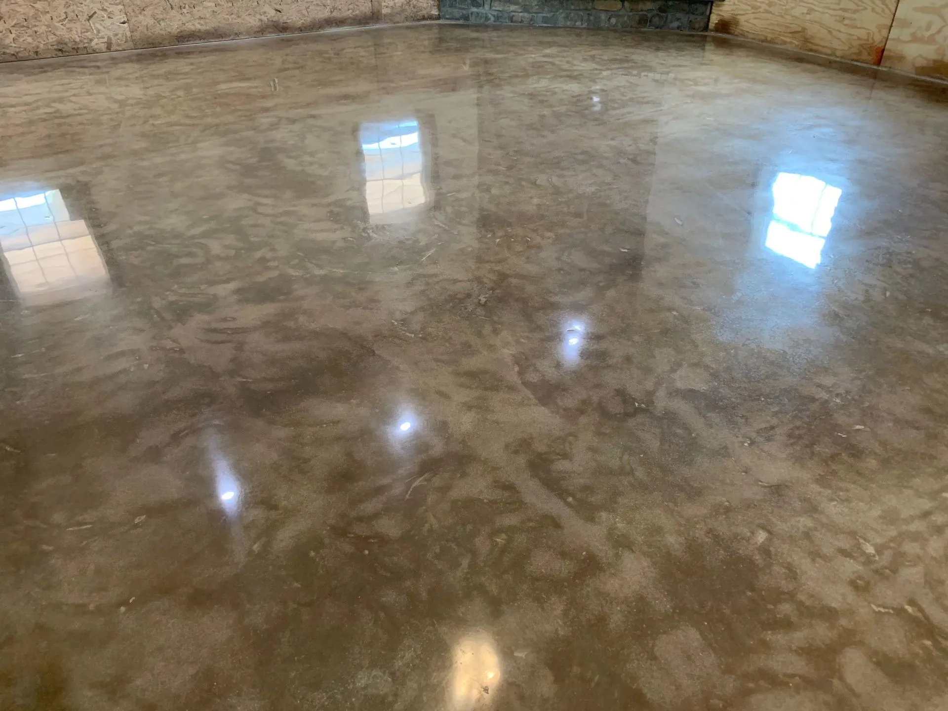 A shiny concrete floor in a room with a window reflected in it.