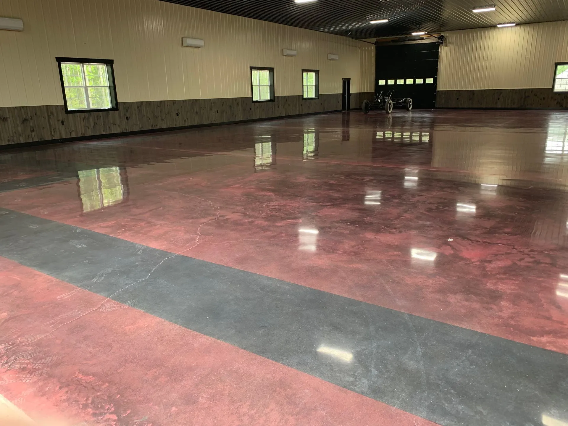 A large empty room with a red and black concrete floor.