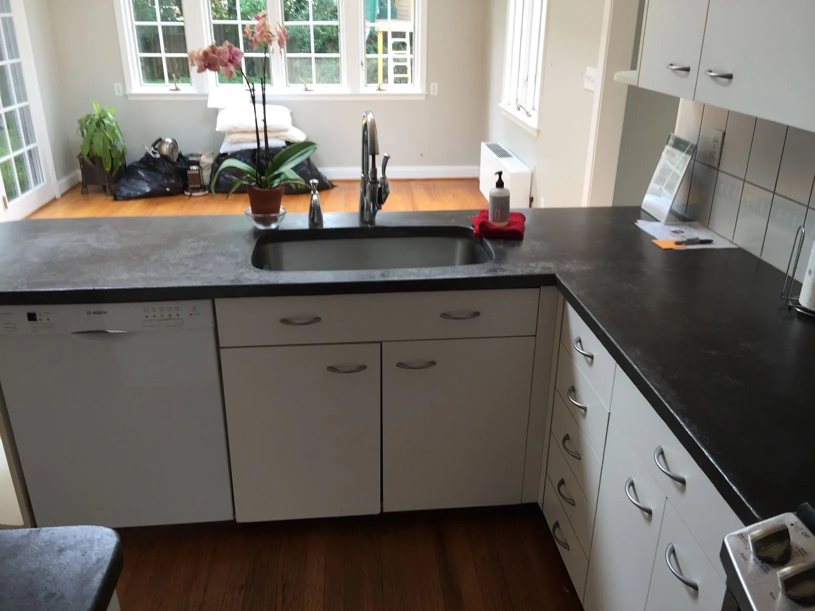 A kitchen with polished black counter tops and white cabinets