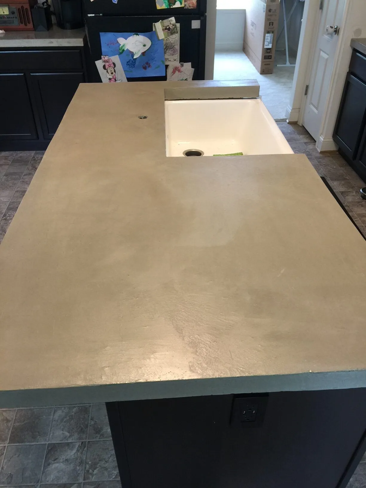 A kitchen with a large concrete counter top and a sink.