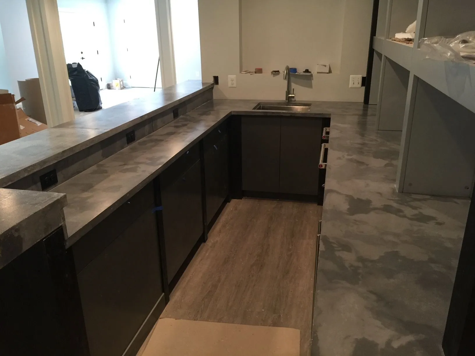 A kitchen with concrete counter tops and a sink