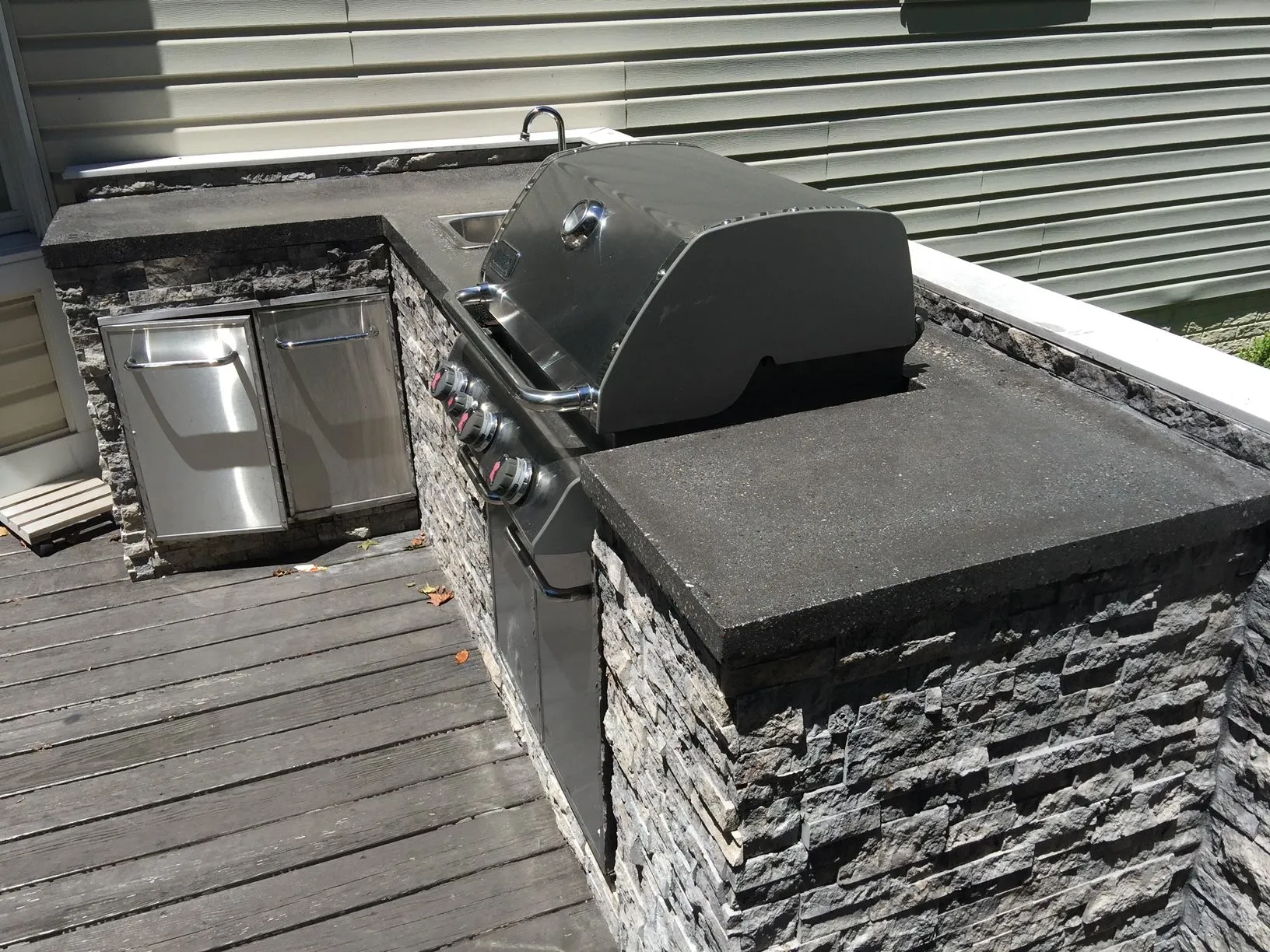 A grill is sitting on top of a wooden deck.
