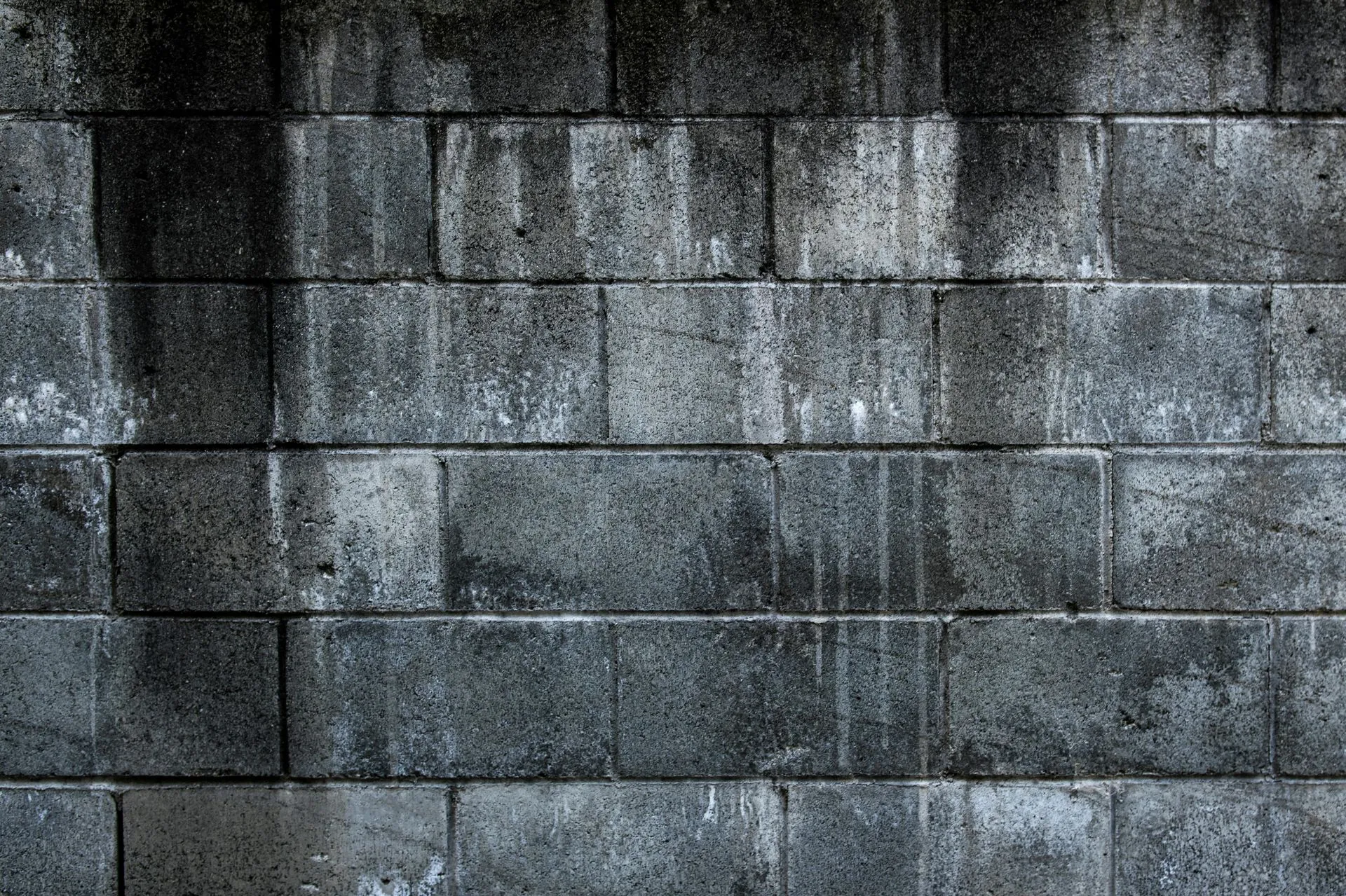 Weathered dark grey concrete block wall texture