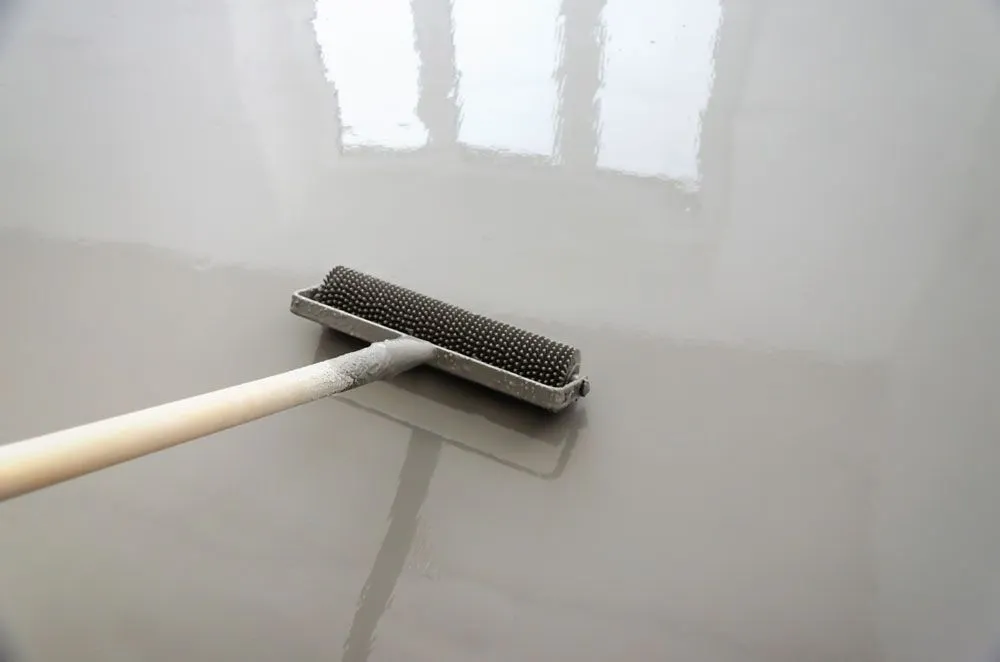 A person is using a roller on a concrete floor.