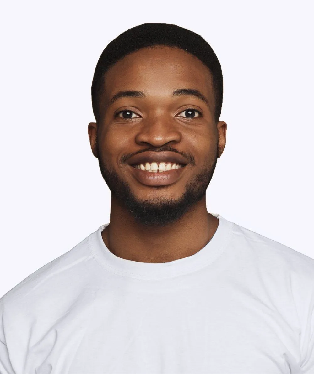 A man with a beard is wearing a white shirt and smiling.