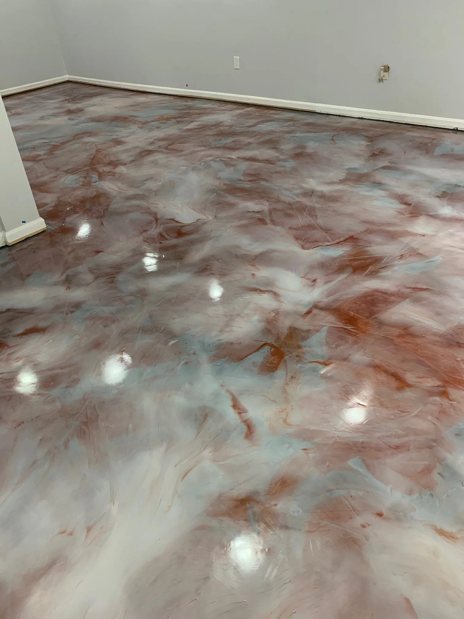 Glossy epoxy floor with red and white marbling in an empty room