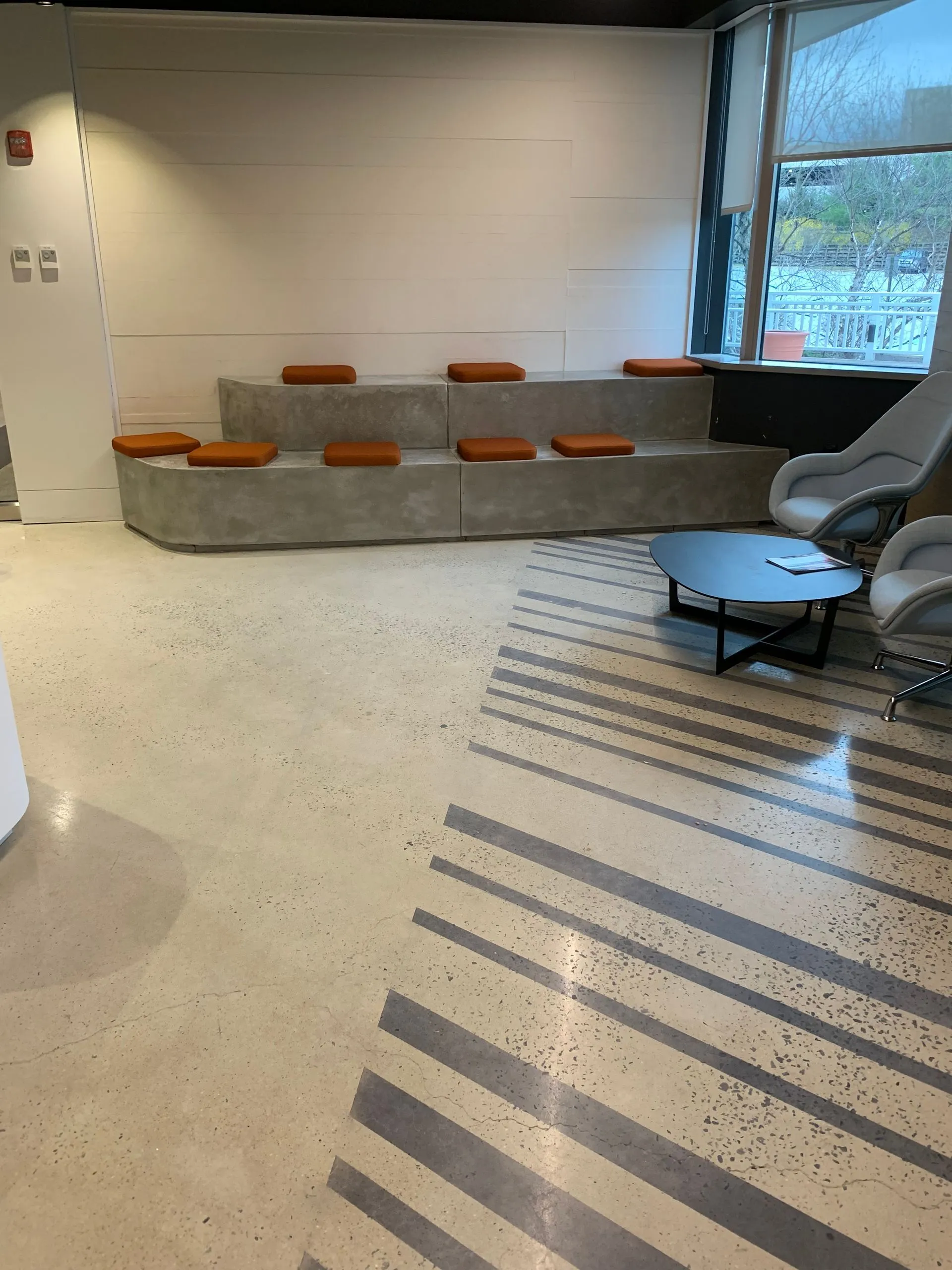 Polished concrete floor with a striped inlay in a commercial lounge with built-in seating