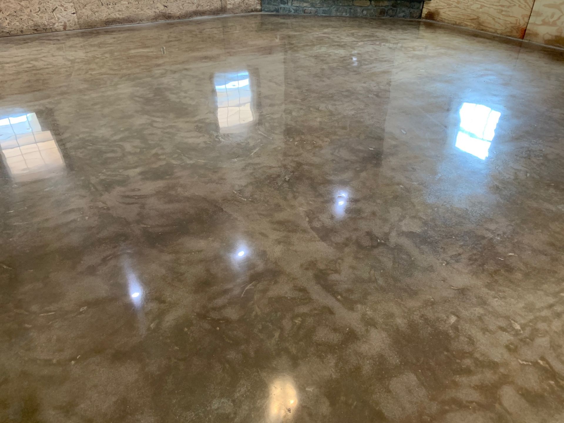 A shiny concrete floor in a room with a window reflected in it.